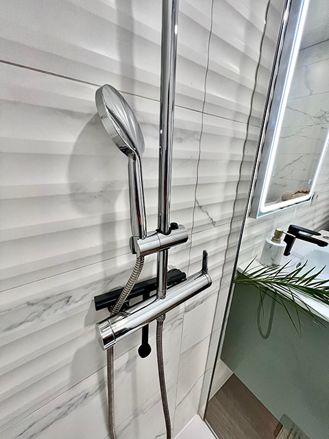 Douche à l'italienne dans la salle de bain de l'appartement, finition minimaliste et accessoires modernes.