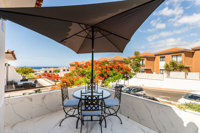 Taras z parasolem i jadalnianą częścią zewnętrzną w otoczeniu kolorowej roślinności.
