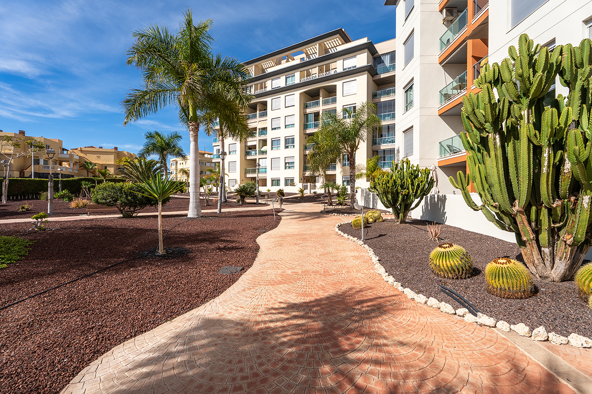 Amplio jardín en un entorno sereno con plantas tropicales y mobiliario exterior en el apartamento vacacional de Golf del Sur, Tenerife