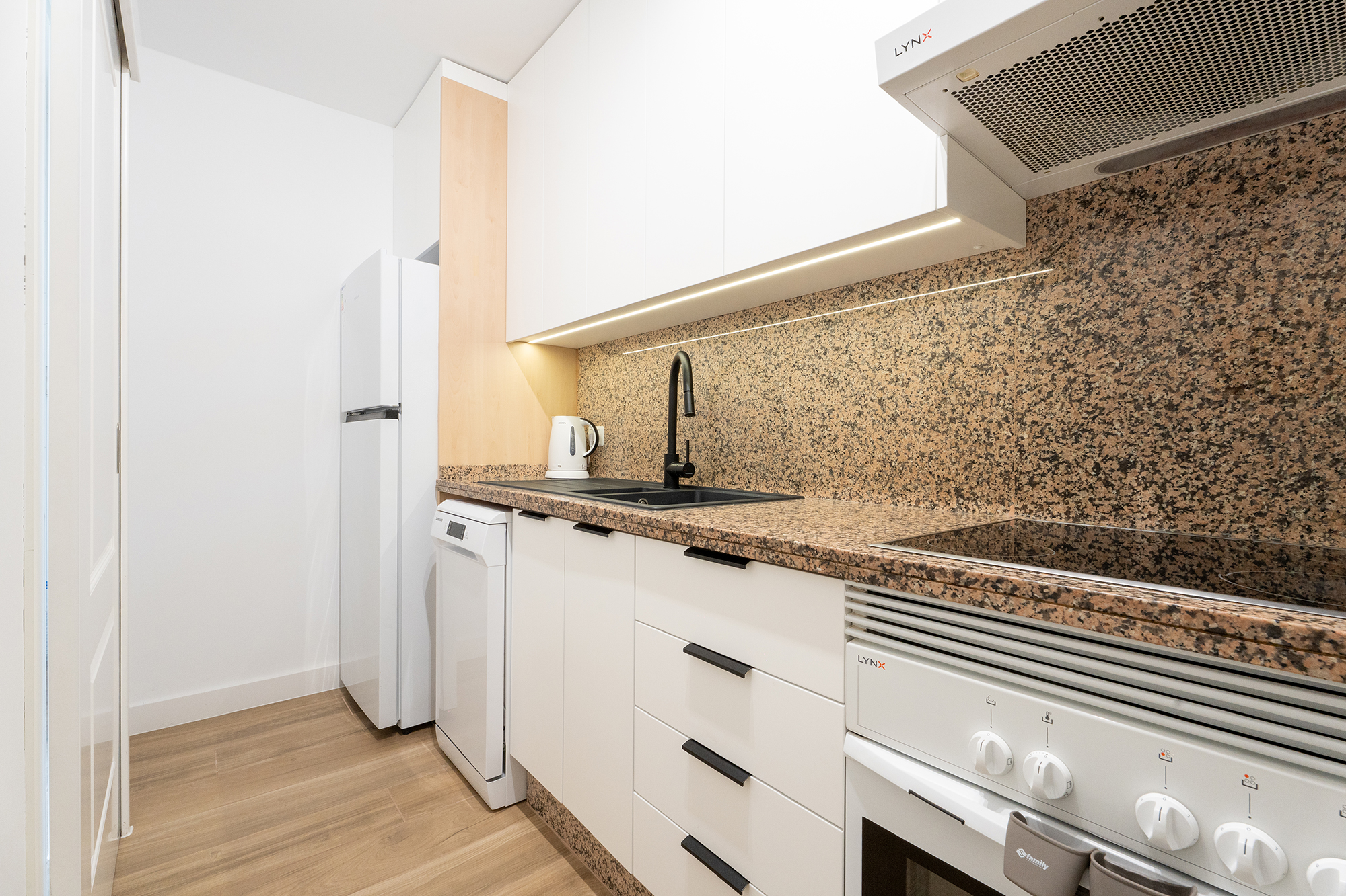 Cocina luminosa con nevera moderna y electrodomésticos en apartamento de alquiler vacacional en Islas Canarias