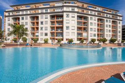 Amplia piscina rodeada de tumbonas y palmeras en apartamento vacacional, Islas Canarias