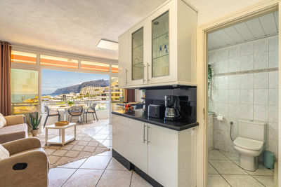 Gran salón luminoso con cómodos sofás y ventanas que ofrecen vistas al océano en un apartamento de Islas Canarias, España.